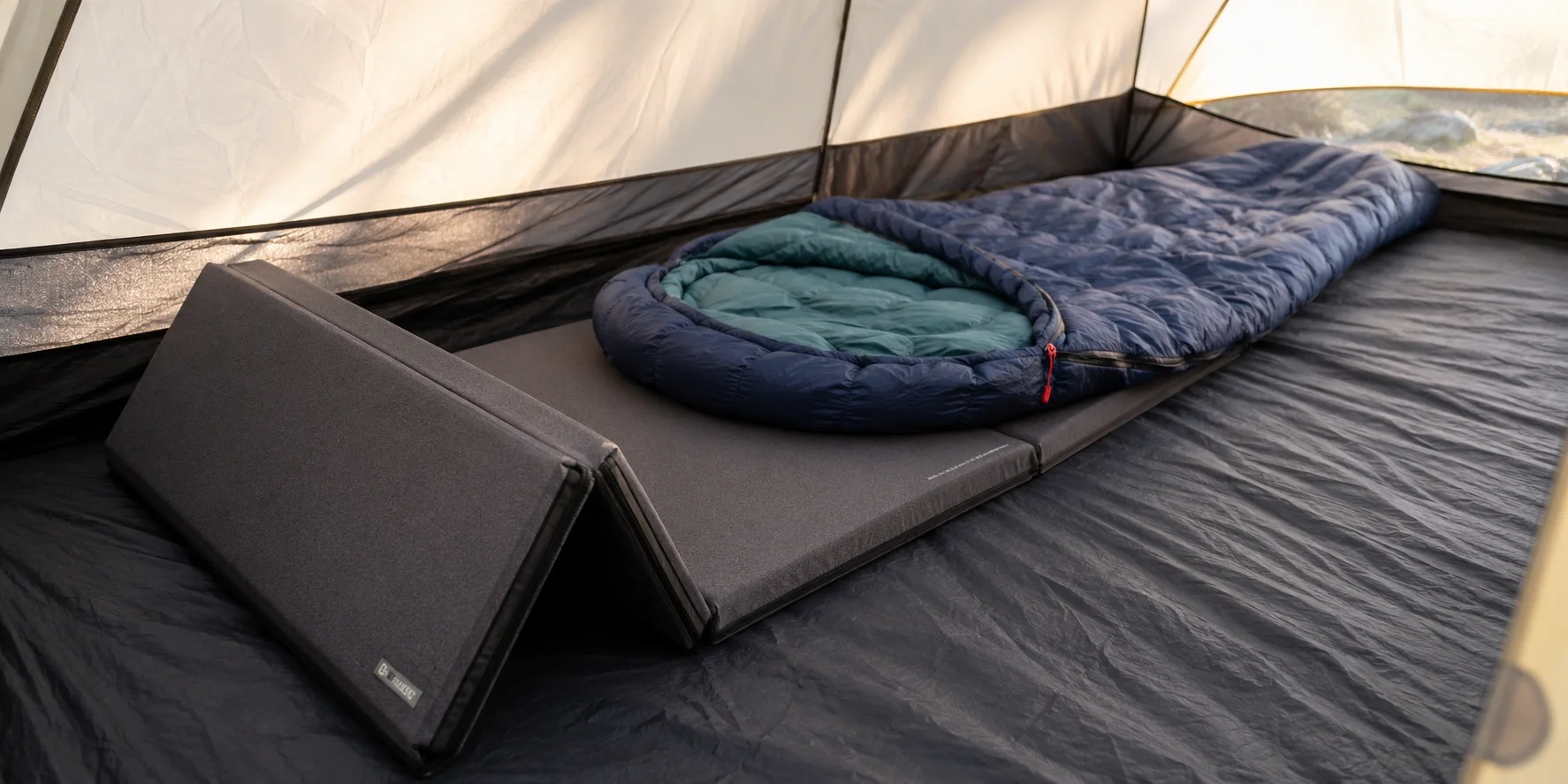Foldable foam camping bed rolled out on tent floor